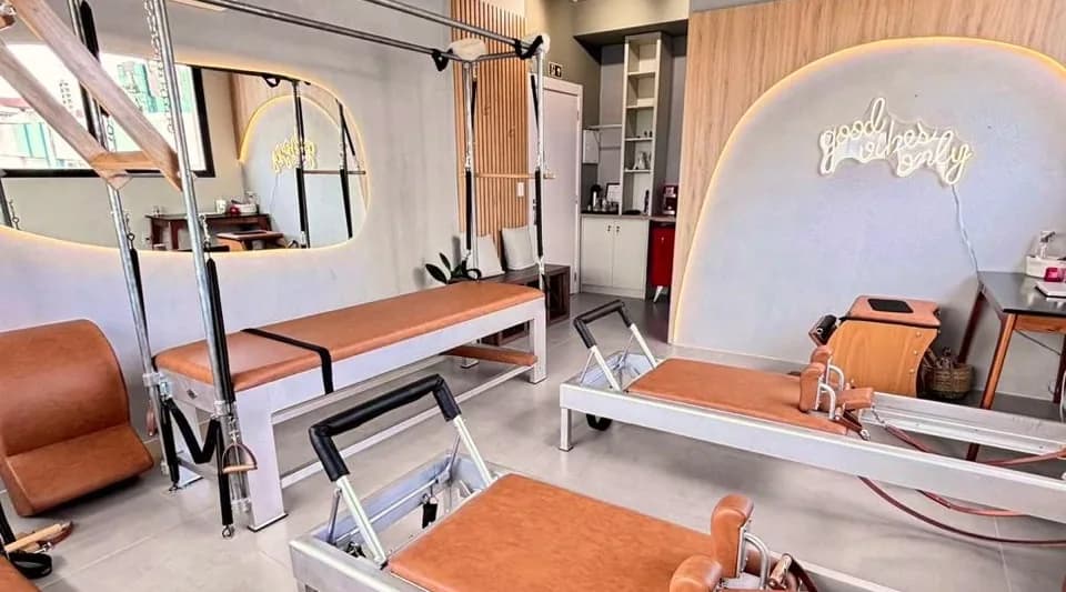 Sala do estúdio Hera Pilates Clássico com Cadillac, Reformers, Chair e a parede em arco iluminada, no Menino Deus, em Porto Alegre